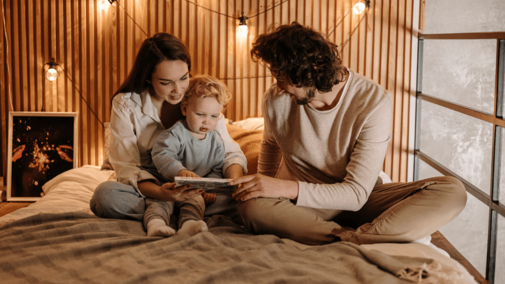 A family sitting on the floor looking at a book