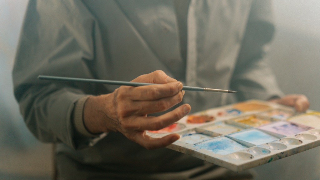 A person is holding a paintbrush and a palette