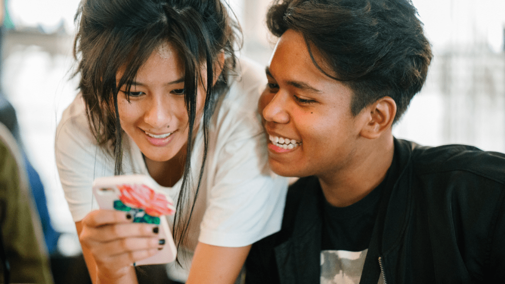 Two people smiling while looking at a cell phone