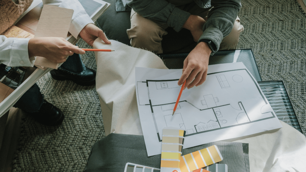 two people sitting on a couch looking at blueprints