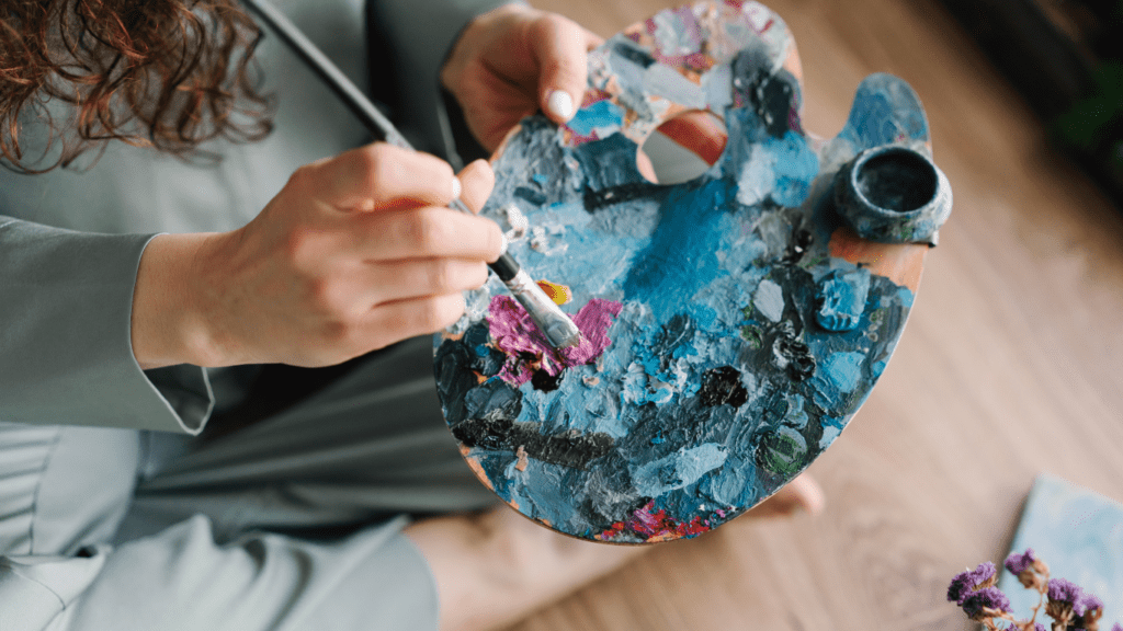 a person sitting on the floor holding a paint palette