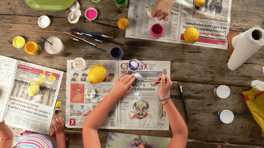 Two children are sitting on the floor and drawing with crayons