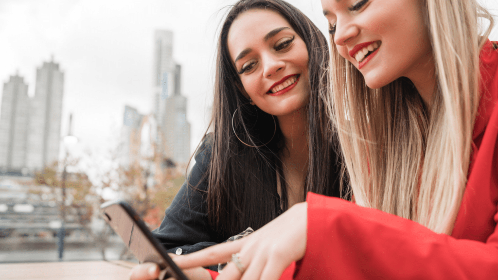 Two people smiling while looking at a cell phone