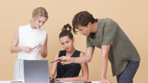 three people looking at a laptop on a table