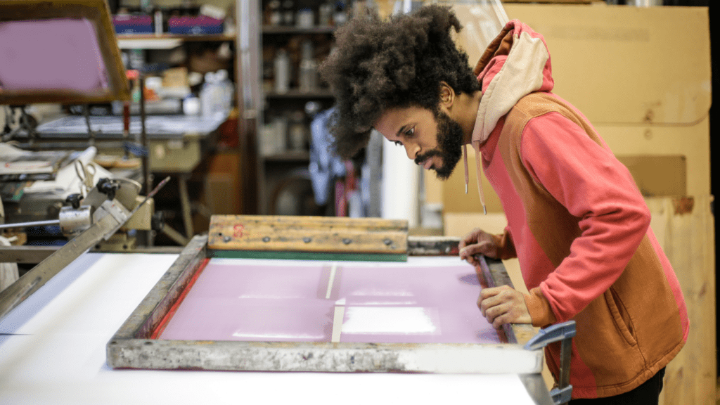 a person is working on a screen printing machine