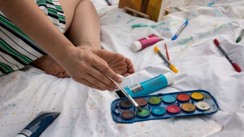 a person sitting on the floor holding a paint palette