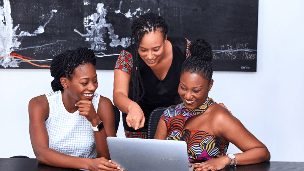 three people looking at a laptop on a table