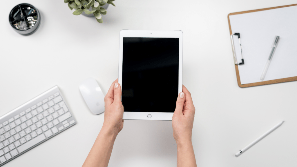 top view of hands holding an ipad on a wooden table